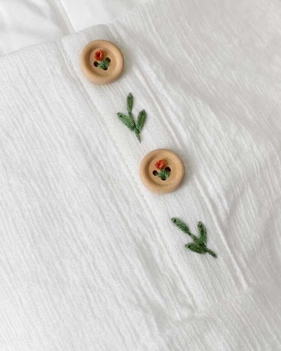 zoom in floral embroidery on the white linen dress