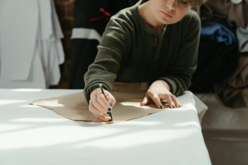 Artist sketching custom clothing designs, showcasing the creative process in fashion design.